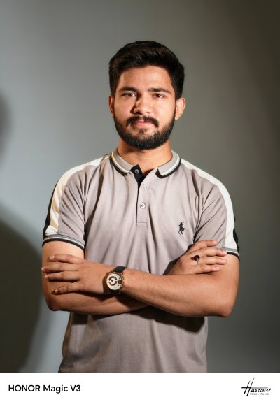 A person with a beard crossing his armsDescription automatically generated